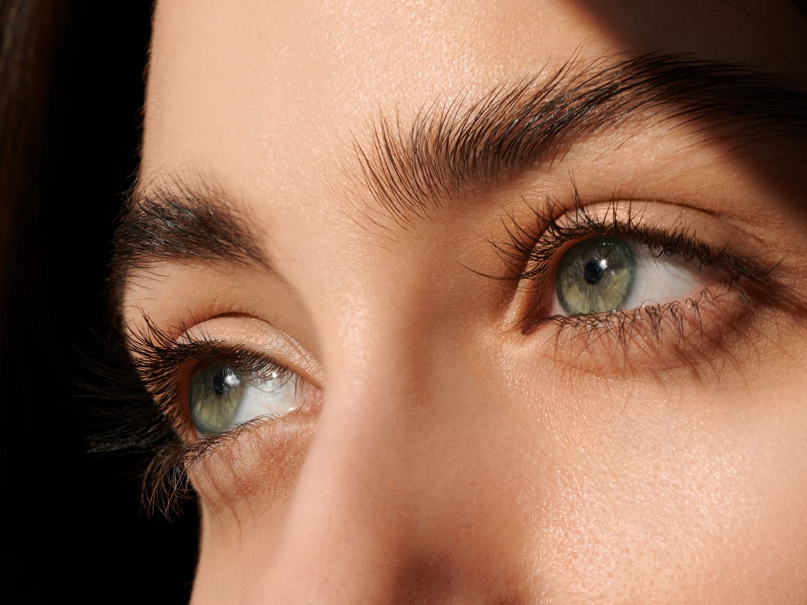 A close view of a woman's eyes with hard, raking light across the brow and cheek